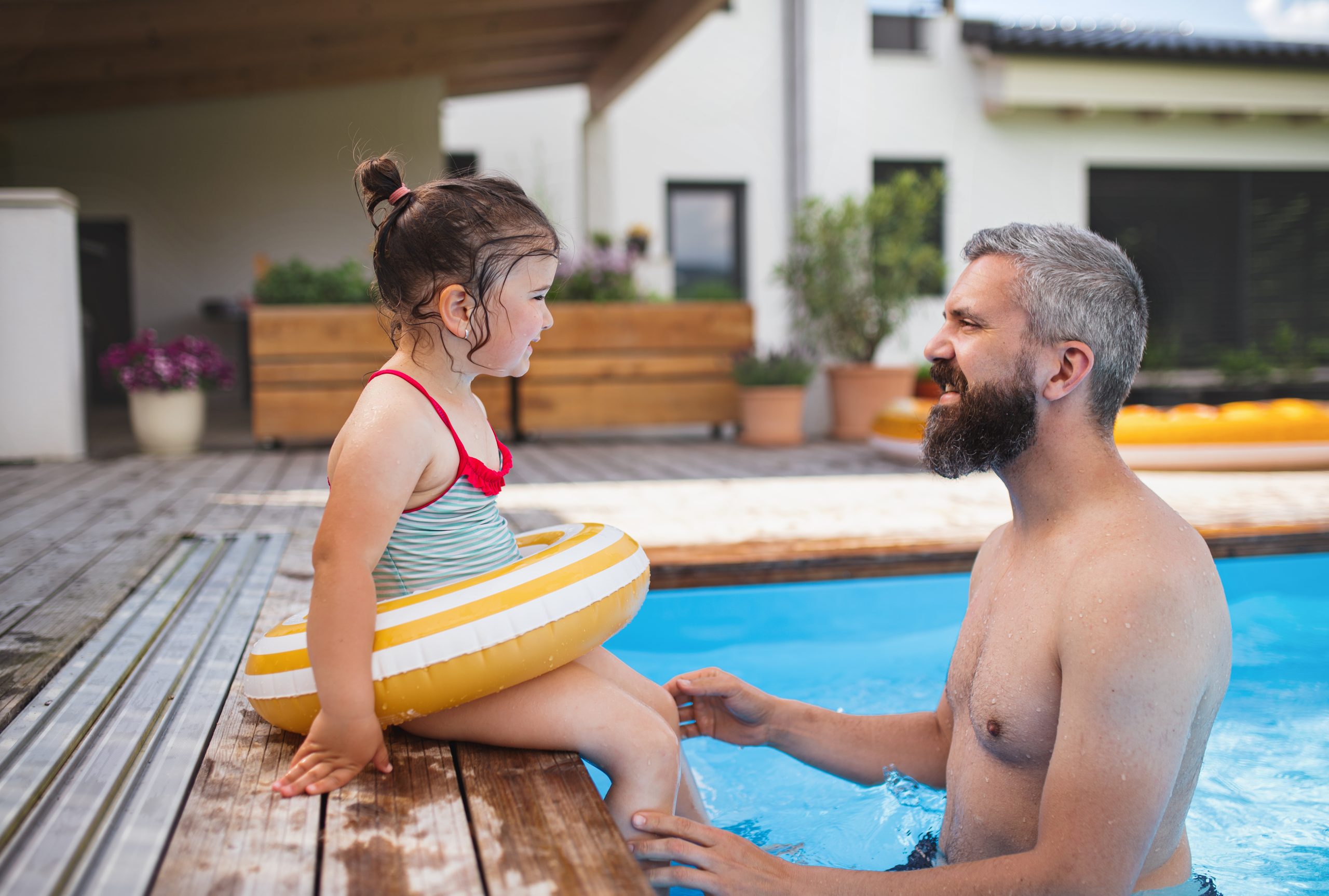 Father with daughter playing in swimming pool.